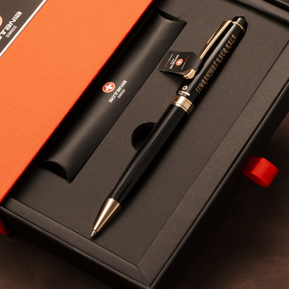 A black ballpoint pen with gold trim and Chinese characters engraved on the barrel, presented in a black gift box with an orange lid. A black cylindrical tube with a Swiss flag logo is also included.