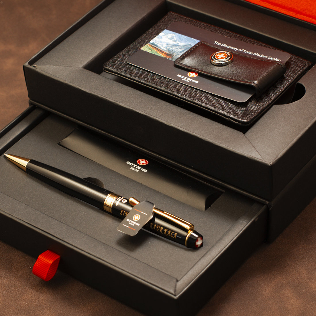 A luxury gift set featuring a black and gold ballpoint pen and a dark brown leather wallet, both engraved with 'Volkswagen' and the brand's logo, presented in an open black gift box.