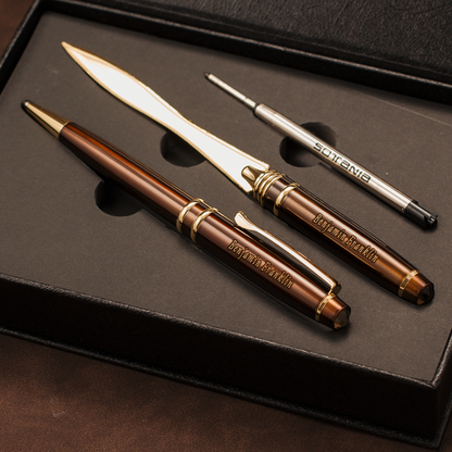 A luxury three-piece writing and stationery set in a black presentation box, featuring a brown and gold ballpoint pen, a silver and gold letter opener, and a silver and gold pencil eraser. The brand 'Briefforts' is clearly engraved on the metal pieces.