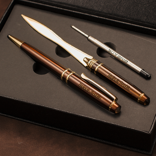A luxury three-piece writing and stationery set in a black presentation box, featuring a brown and gold ballpoint pen, a silver and gold letter opener, and a silver and gold pencil eraser. The brand 'Briefforts' is clearly engraved on the metal pieces.