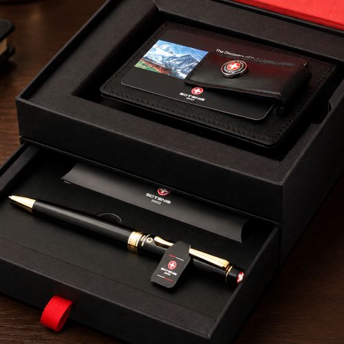 Swiss Army-themed gift set in a black presentation box, featuring a black leather wallet with a mountain photo and Swiss Army logo, a black pen with gold trim, and branded paper inside a red-lined box.