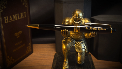 A personalized black and gold pen engraved with 'Dr. Nawras Radwan' inside a blue presentation box next to a silver refill