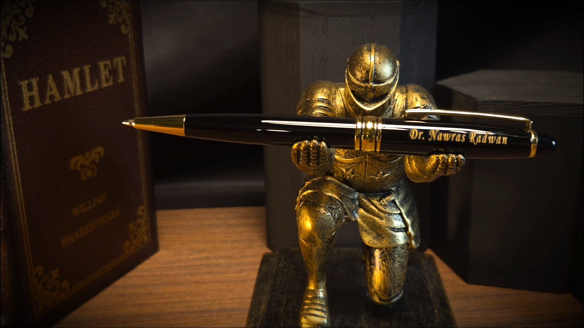 A personalized black and gold pen engraved with 'Dr. Nawras Radwan' inside a blue presentation box next to a silver refill